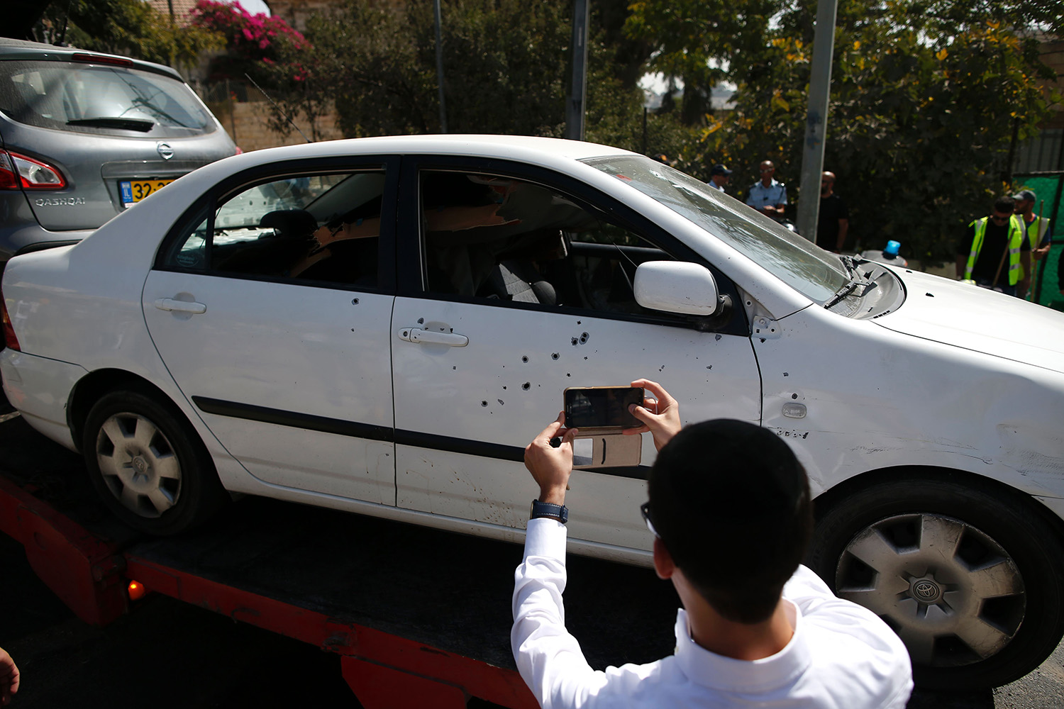 Man taking photos of a damaged car with his phone camera