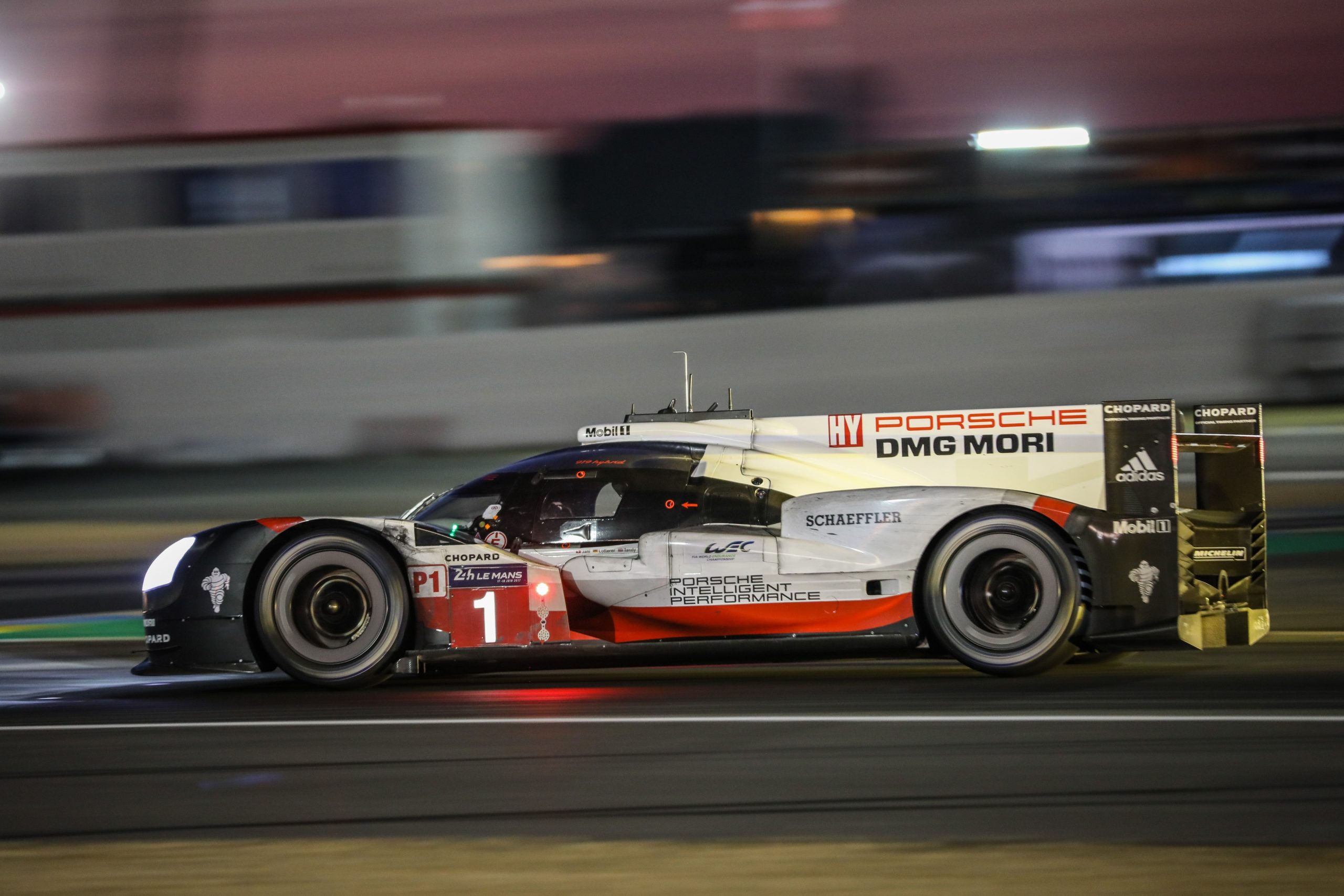 A profile view of a Porsche 919 LMP race car driving at night during the 2017 24 Hours of Le Mans race.