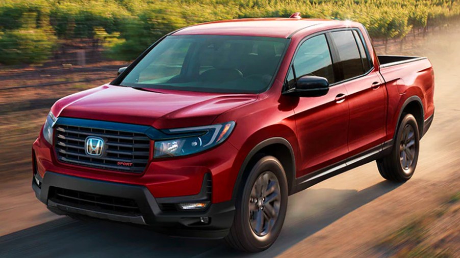 A red 2022 Honda Ridgeline midsize pickup truck is driving off-road.