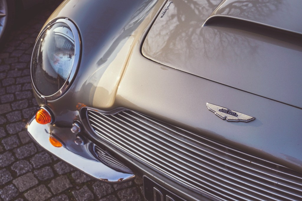Detail shot of the silver headlight unit of an Aston Martin DB5 sports car.