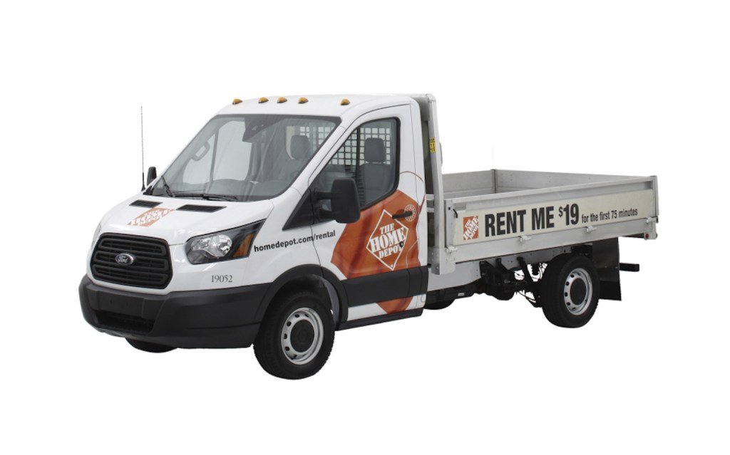 Ford Transit flatbed truck with Home Depot badges on its doors.