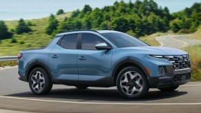 A blue 2022 Hyundai Santa Cruz is driving on the road.