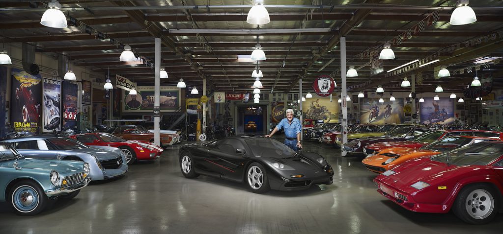 Jay Leno in his garage leaning against a McLaren F1.