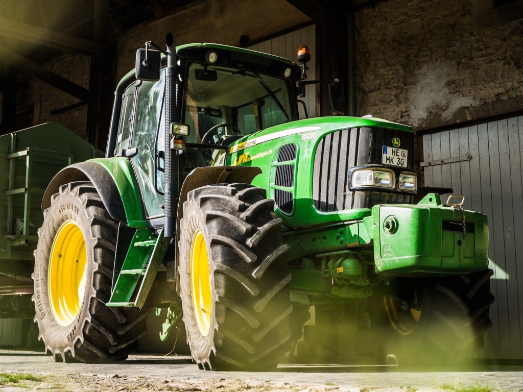Large 4WD John Deere tractor parked in a barn.