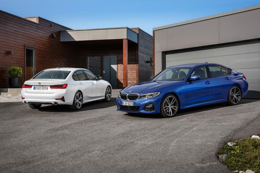 Two certified pre-owned 2019 BMW 3 Series sedans by a garage