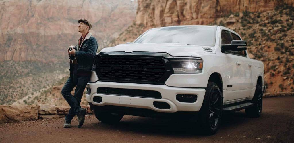 Man leaning against a white 2022 Ram 1500, the full-size pickup truck with the best gas mileage in 2022