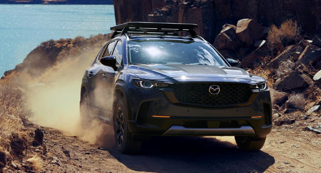 A blue 2023 Mazda CX-50 Turbo Meridian Edition is driving down a hill off-road.