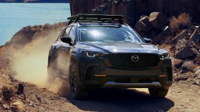 A blue 2023 Mazda CX-50 Turbo Meridian Edition is driving down a hill off-road.