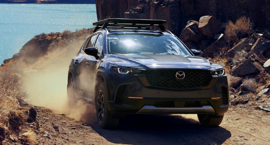 A blue 2023 Mazda CX-50 Turbo Meridian Edition is driving down a hill off-road.