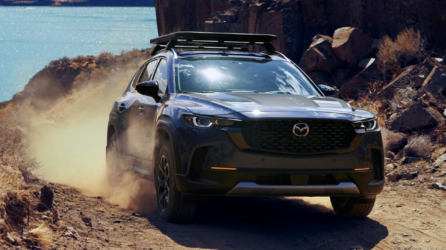A blue 2023 Mazda CX-50 Turbo Meridian Edition is driving down a hill off-road.