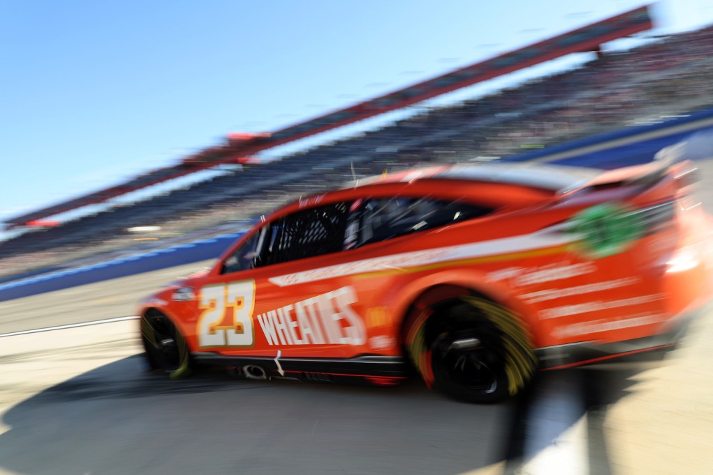 A red NASCAR Next Gen car blurring past the camera during a race.