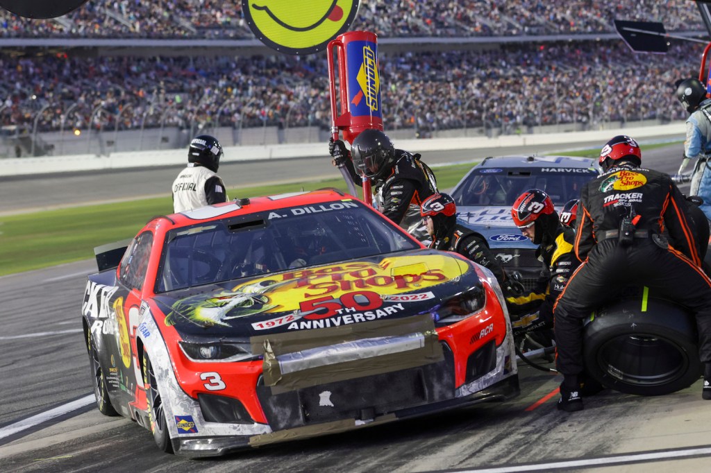 The #3 NASCAR Next Gen car coming in for a pit stop, crew member fueling it up and changing the tires.