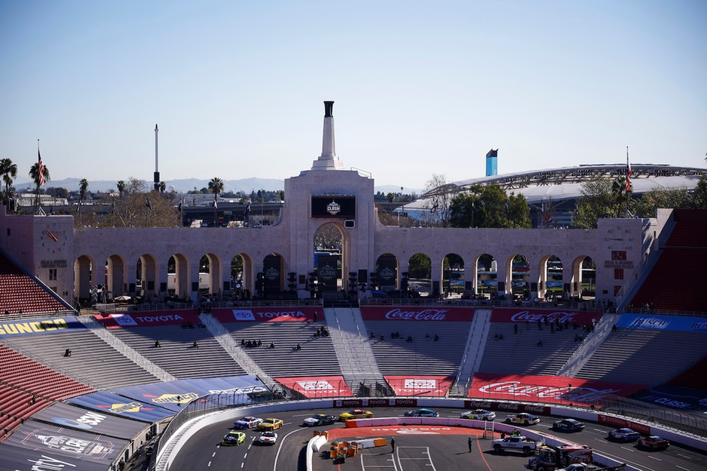 Next Gen NASCAR cars practicing for a race in an empty stadium.