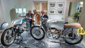 Norbert Kaaden, Christian Steiner, and Lutz Langer next to a MZ RD 125 (left) and a a DKW 350 RM at a two-stroke motorcycle show honoring Walter Kaaden