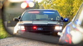 Ford interceptor SUV framed in a vehicle's rearview mirror during a traffics top.