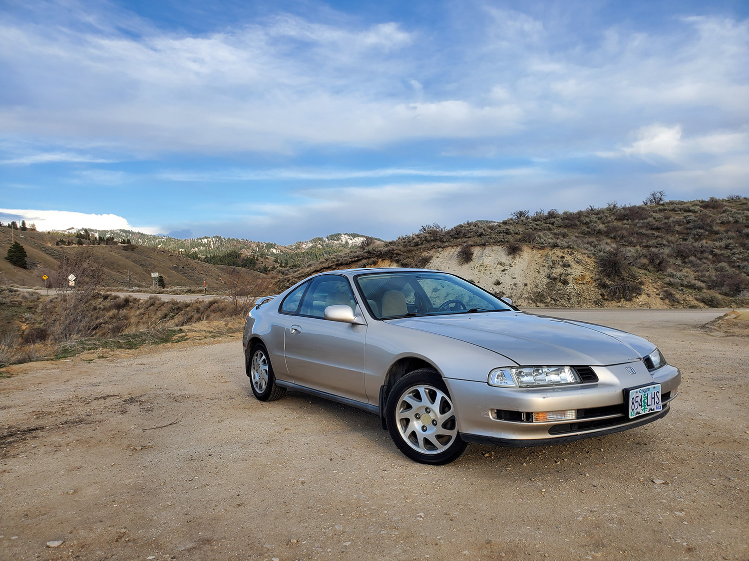 Silver 1996 Honda Prelude Si parked on mountain road with snow caps in background