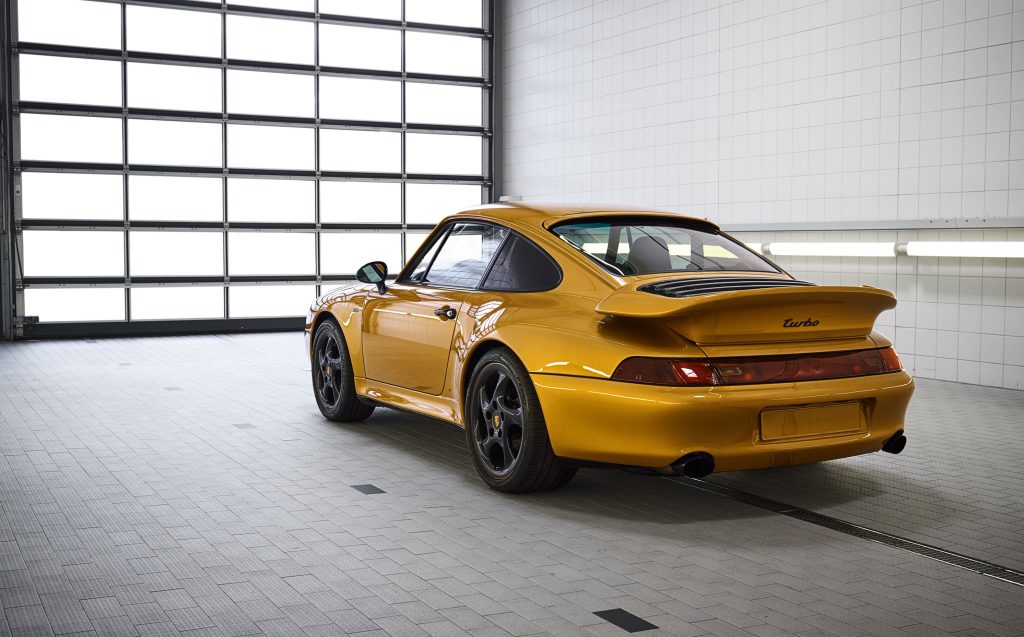 The rear 3/4 view of the gold-colored 'Project Gold' 993 Porsche 911 Turbo in a white garage