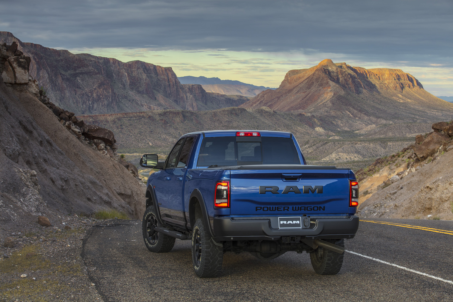 Blue Dodge Power Wagon parked on a road above a sandy mountain range.