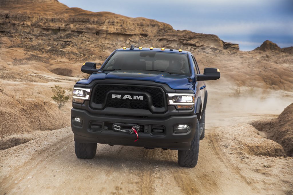 Blue Ram power wagon driving up a dirt trail in the desert.