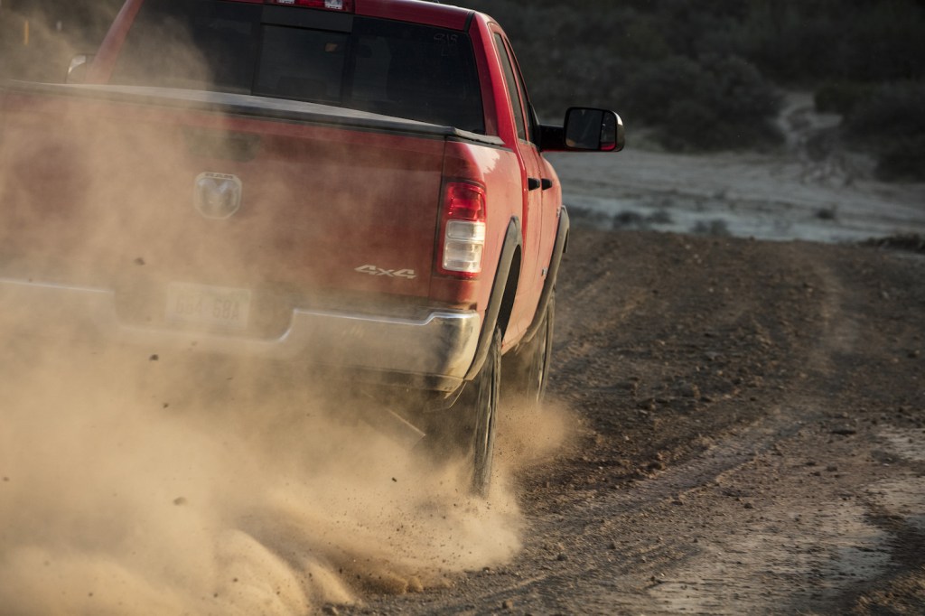 Ram Power Wagon truck off-roading, a cloud of dust around its tires.