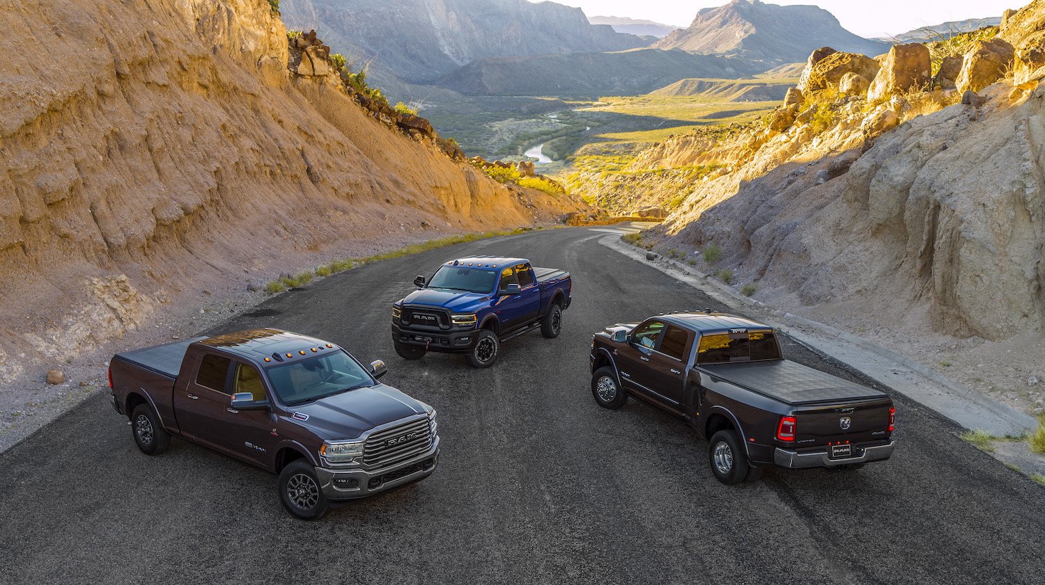 Three Ram pickup trucks parked in a mountain pass.
