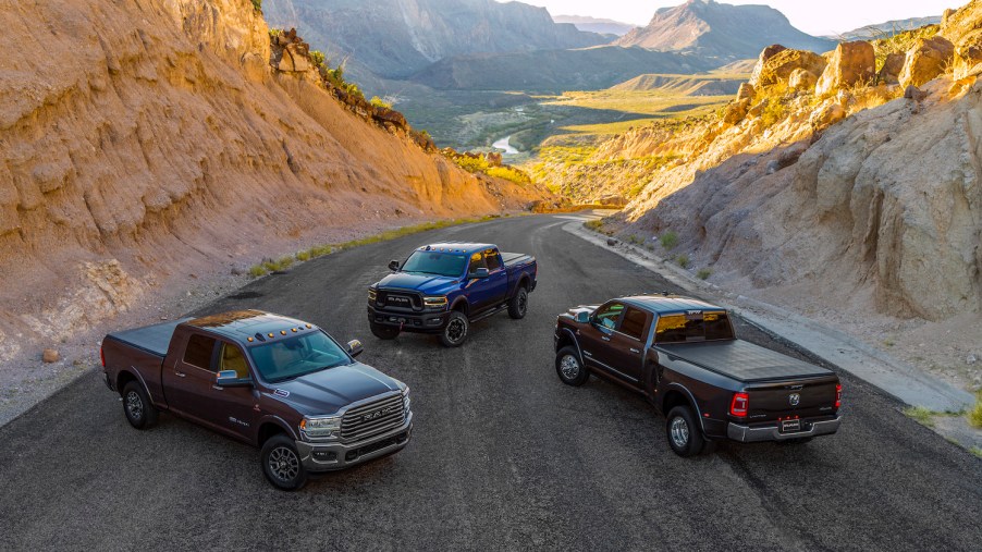 Three Ram pickup trucks parked in a mountain pass.