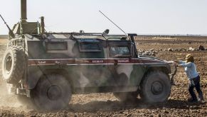 Syrian woman uses her body to block a Cummins-powered Russian military vehicle driving through the desert.