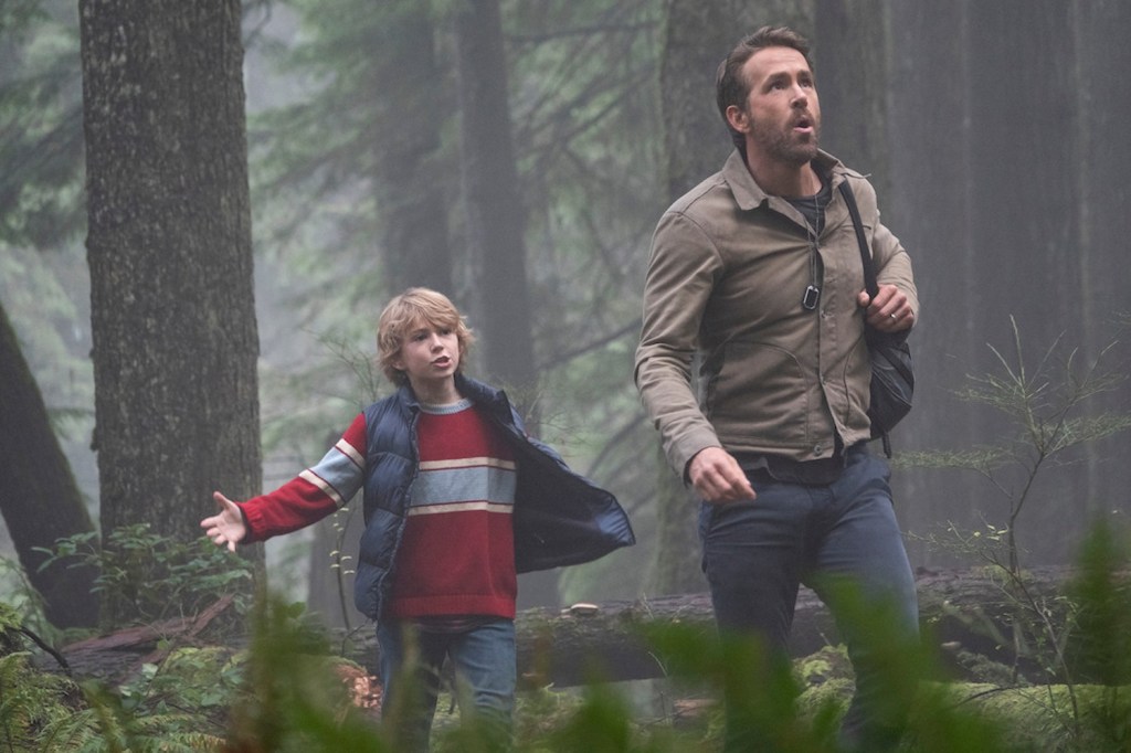 Walker Cobell and Ryan Reynolds walk through the woods during the Netflix film The Adam Project.