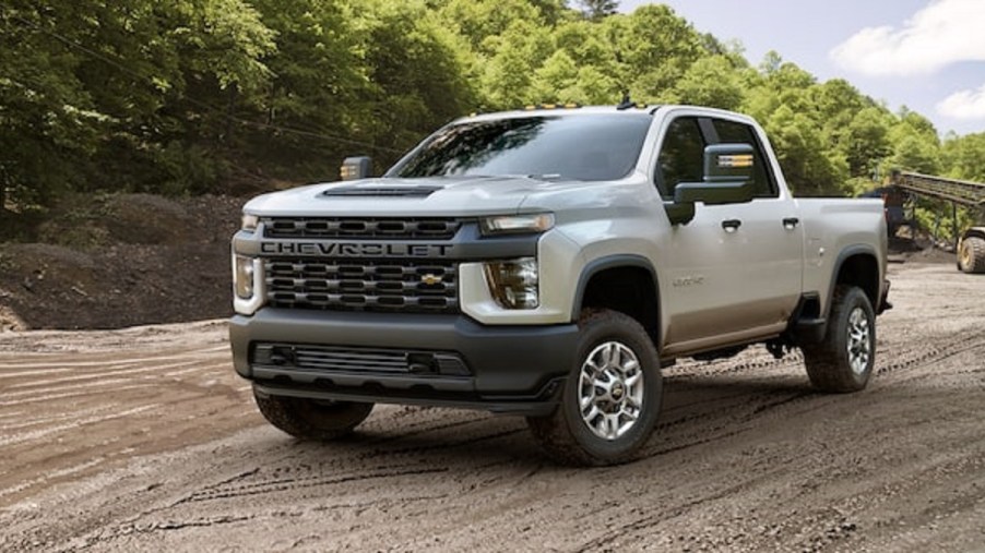 A beige 2022 Chevy Silverado driving through the woods.