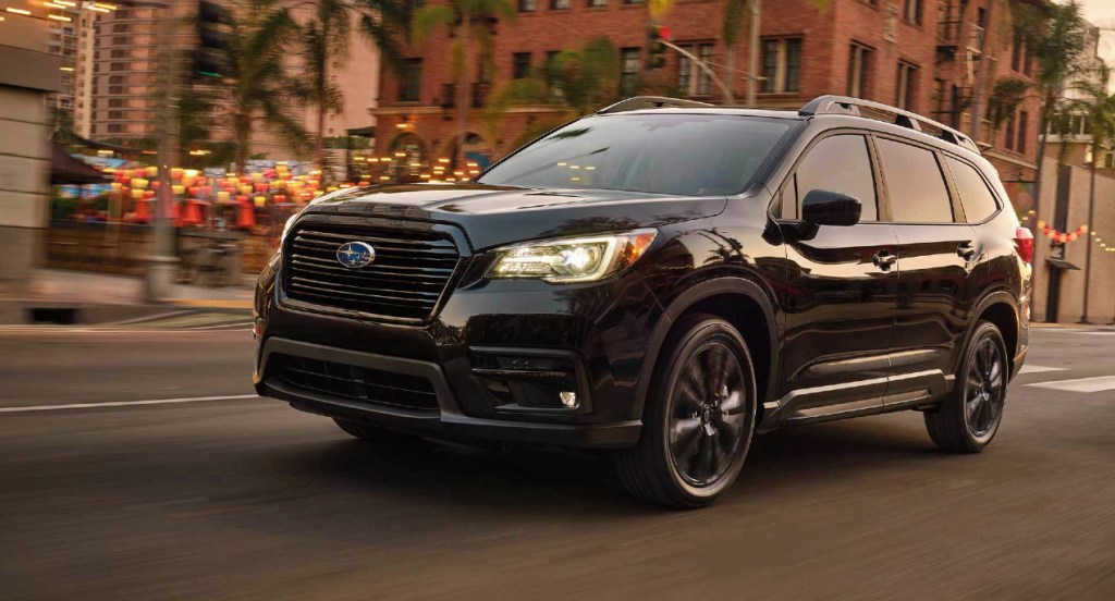 A black 2022 Subaru Ascent mid-size SUV is driving down the road. 