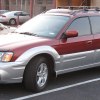A red Subaru Baja sits in a parking lot, showing off its compact size as a small truck.