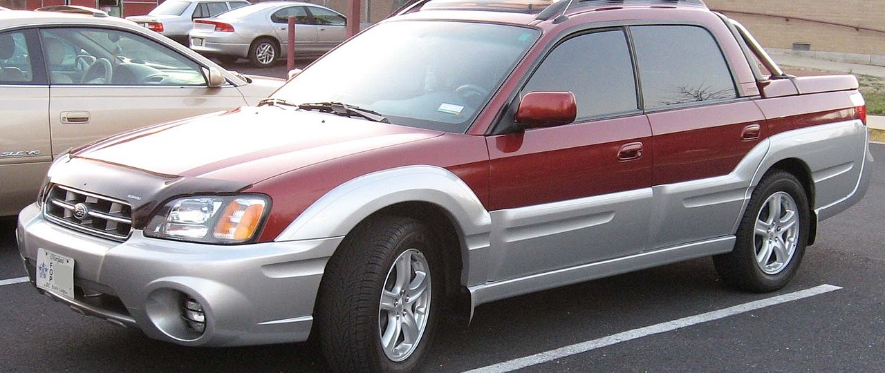 A red Subaru Baja sits in a parking lot, showing off its compact size as a small truck.