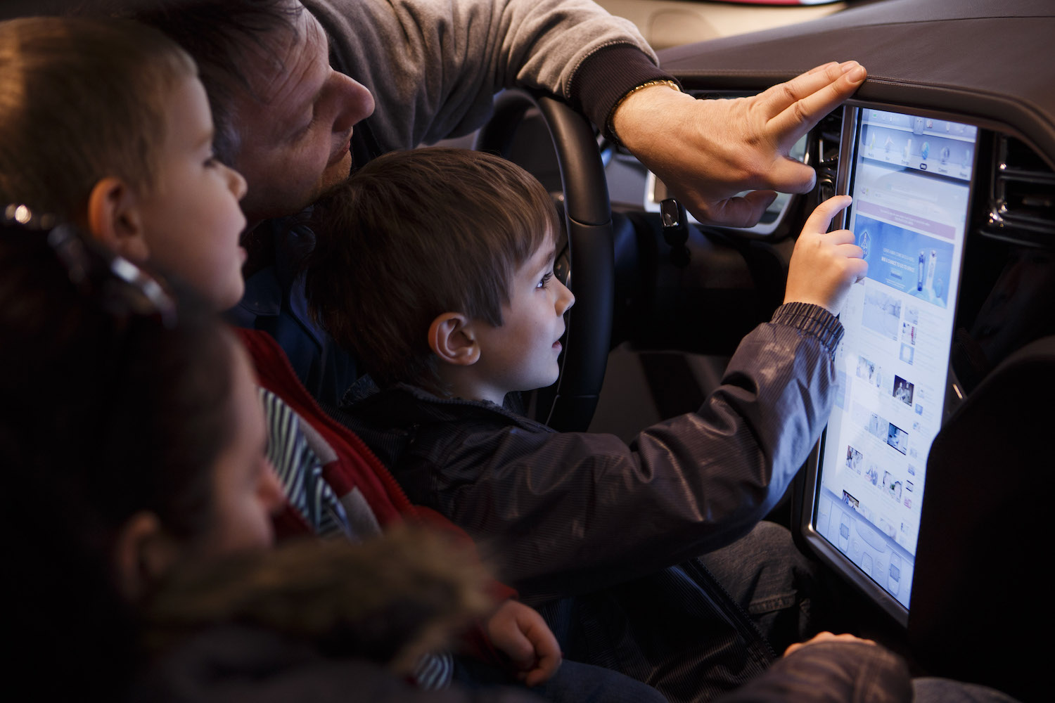 Child playing with a Tesla's 17-inch touchscreen in a dealership. 