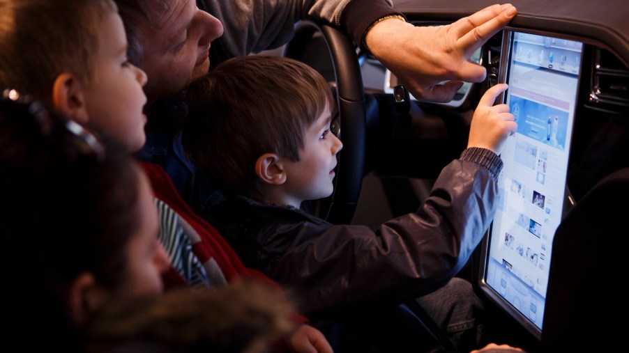 Child playing with a Tesla's 17-inch touchscreen in a dealership.