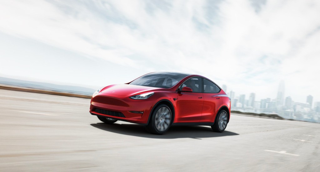 A red Tesla Model Y is driving on the road. How much is the cheapest Tesla model?