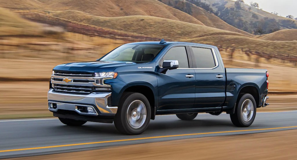 A blue 2022 Chevrolet Silverado 1500 full-size pickup truck is driving on the road. 