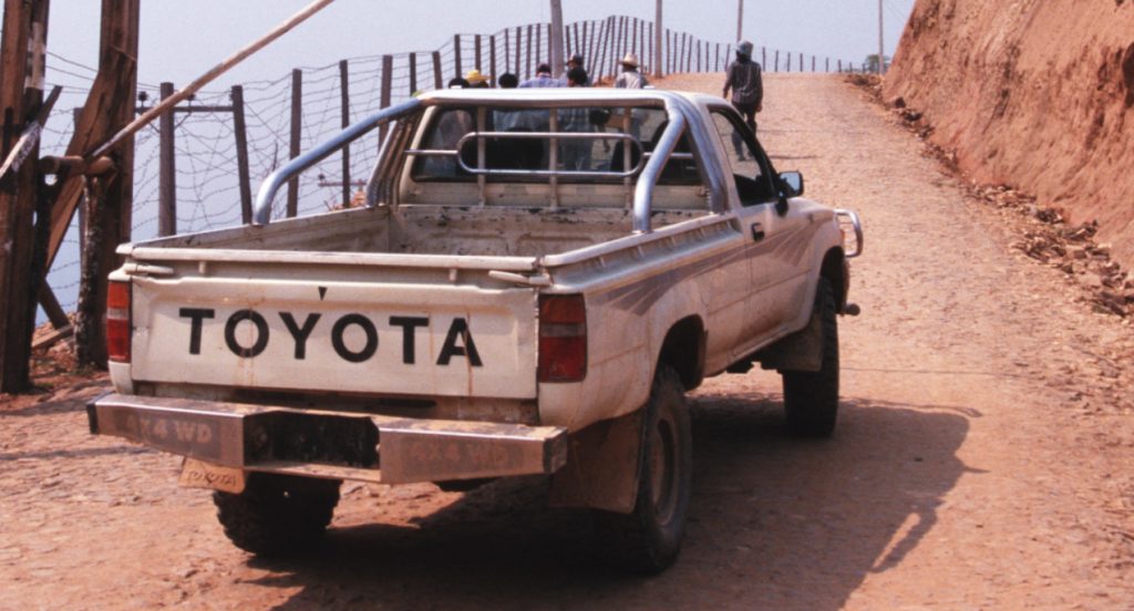 A white Toyota pickup truck drives off-road. 