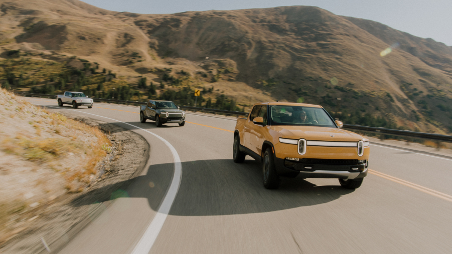 Three 2022 Rivian R1Ts driving on a mountain road, highlighting how the R1T is the best electric pickup truck