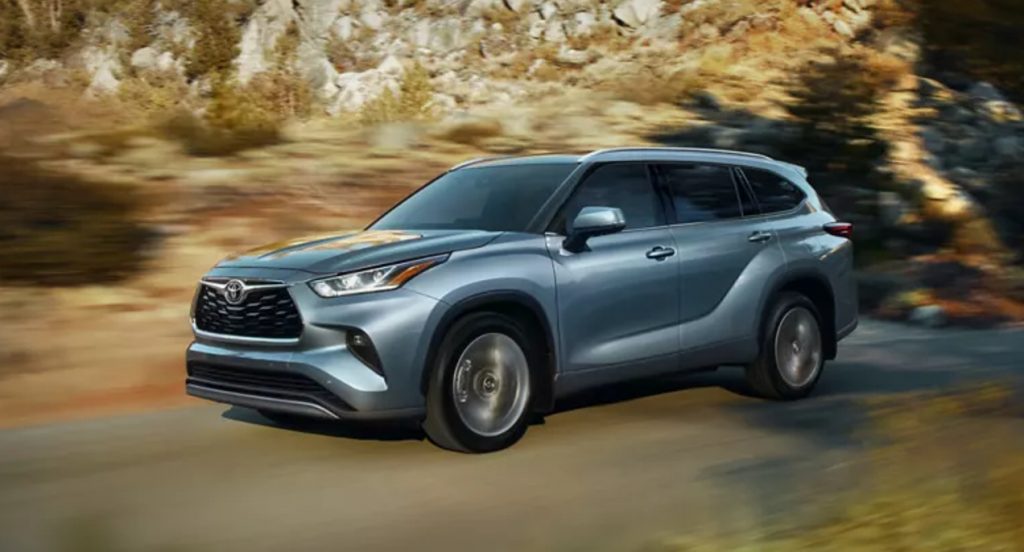 A gray 2022 Toyota Highlander is driving on the road.