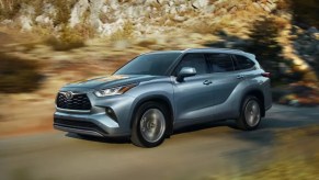 A gray 2022 Toyota Highlander is driving on the road.