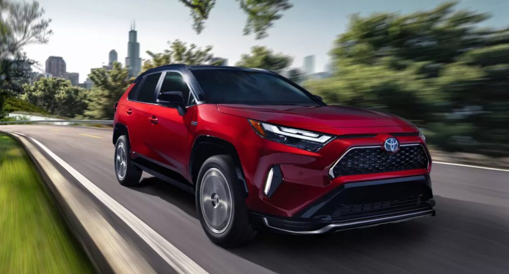 A red 2022 Toyota RAV4 Prime plug-in hybrid SUV drives down the road. 