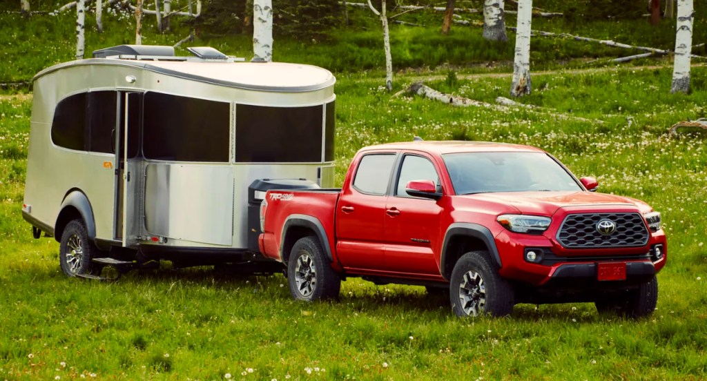 A red 2022 Toyota Tacoma is towing a small trailer. 