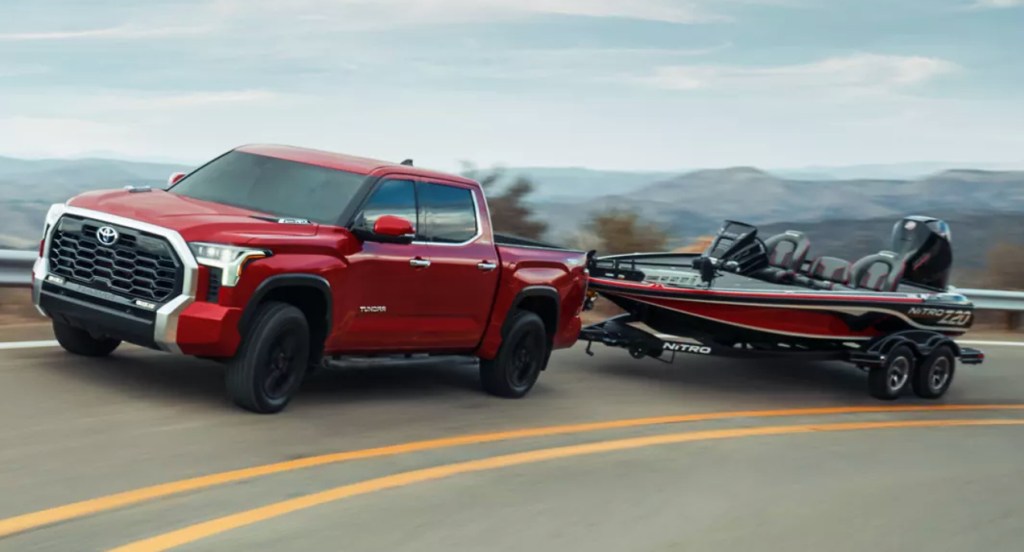 A red 2022 Toyota Tundra is towing a small speed boat.