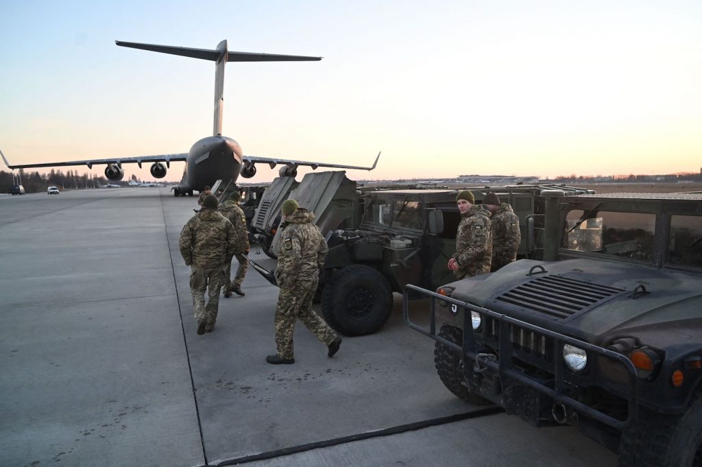 Ukraine military men at an airport, inspecting a row of Humvees donated by the United States.