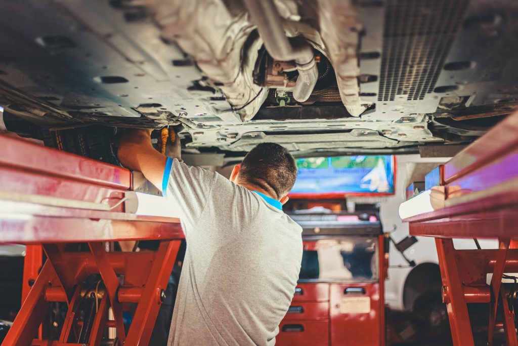 Man under a lift, working on the underside of a vehicle.
