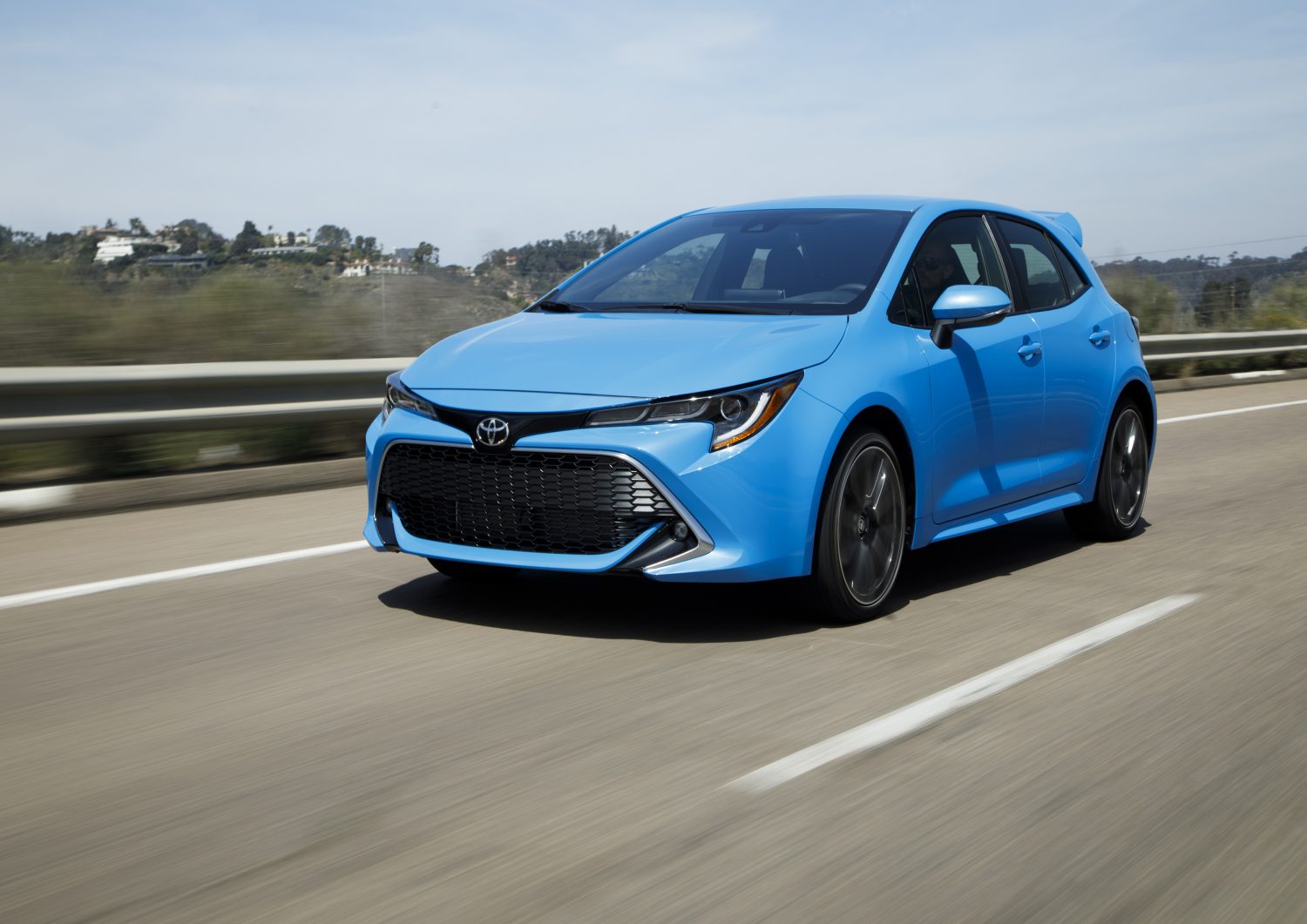 Blue 2022 Toyota Corolla Hatchback in motion, driving down a highway