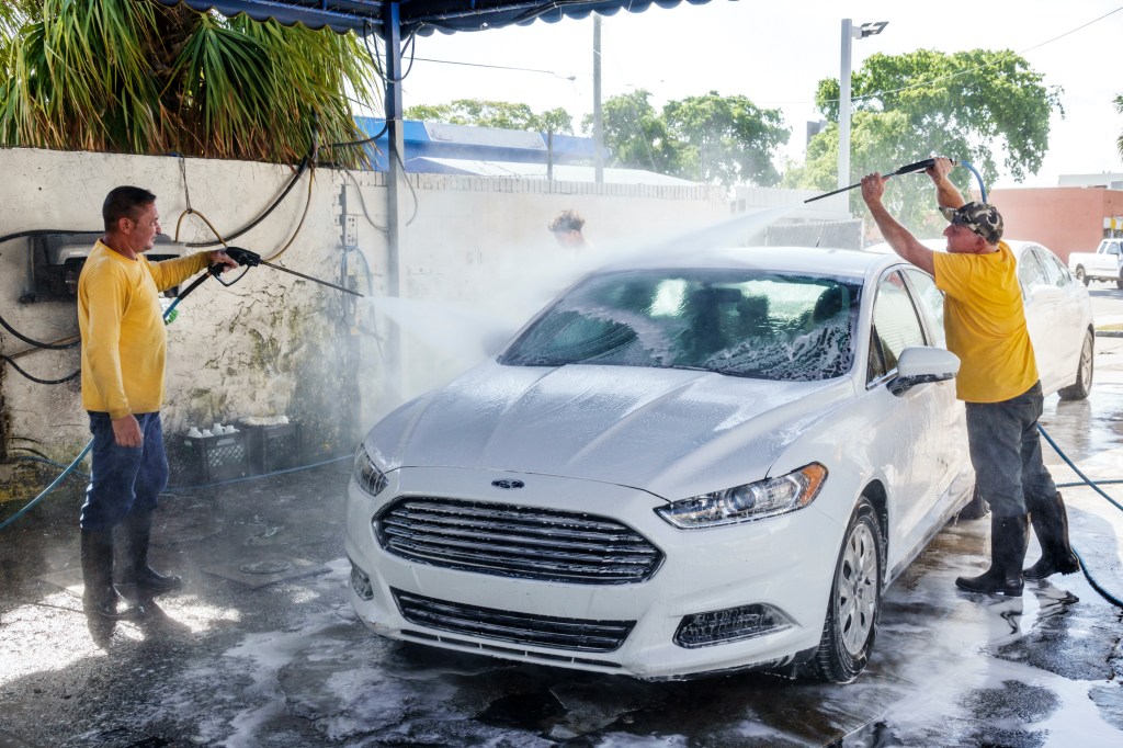Two men wash a car.