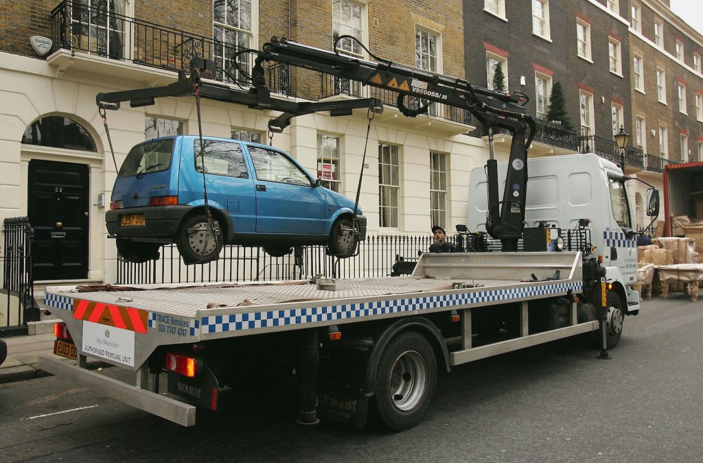A small car gets towed away in England. 