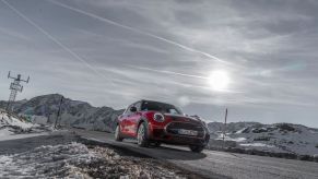 Front view of a 2022 MINI Clubman in red, driving along a road in the winter