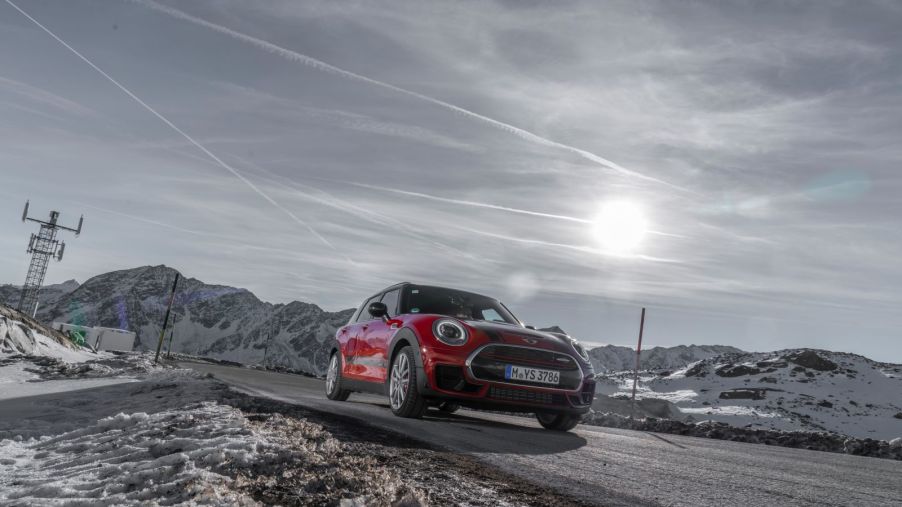 Front view of a 2022 MINI Clubman in red, driving along a road in the winter